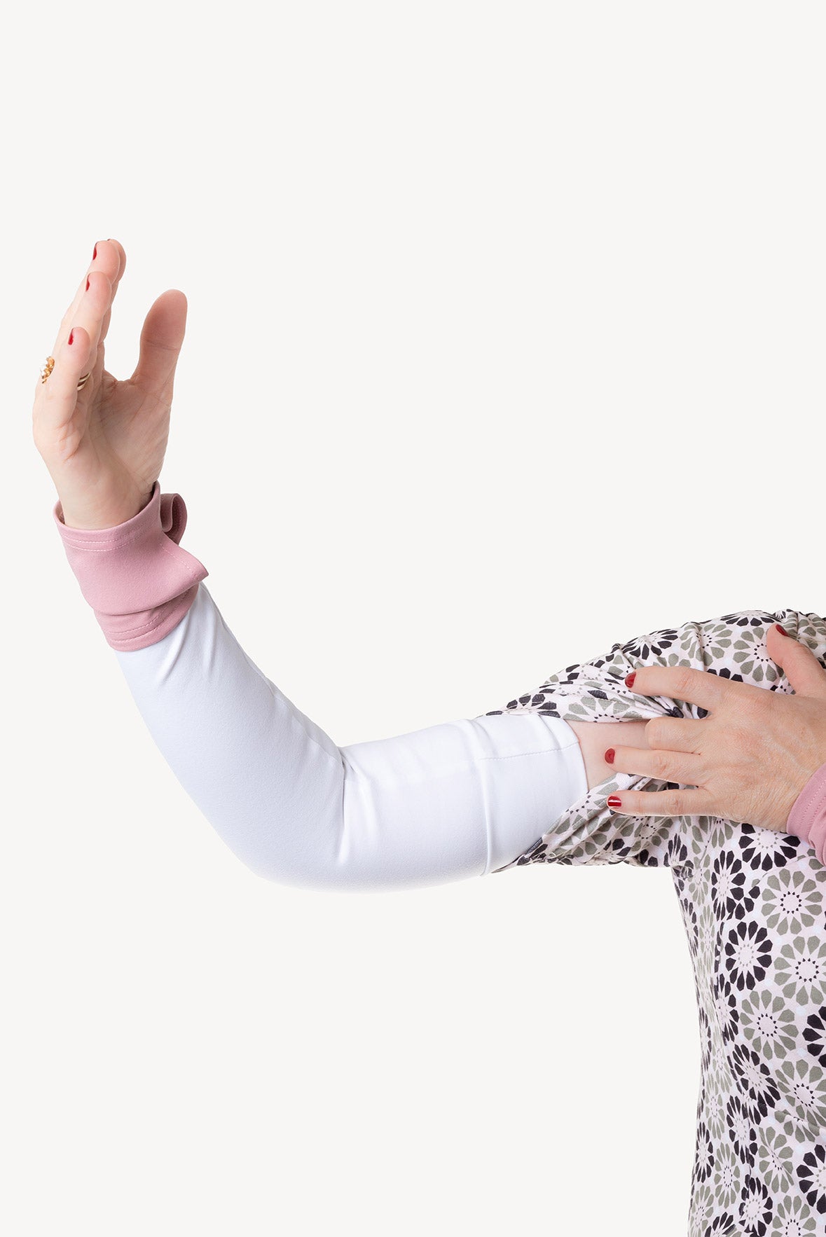 Person wearing a white arm warmer with a pink cuff with a floral patterned dress underneath on a white background