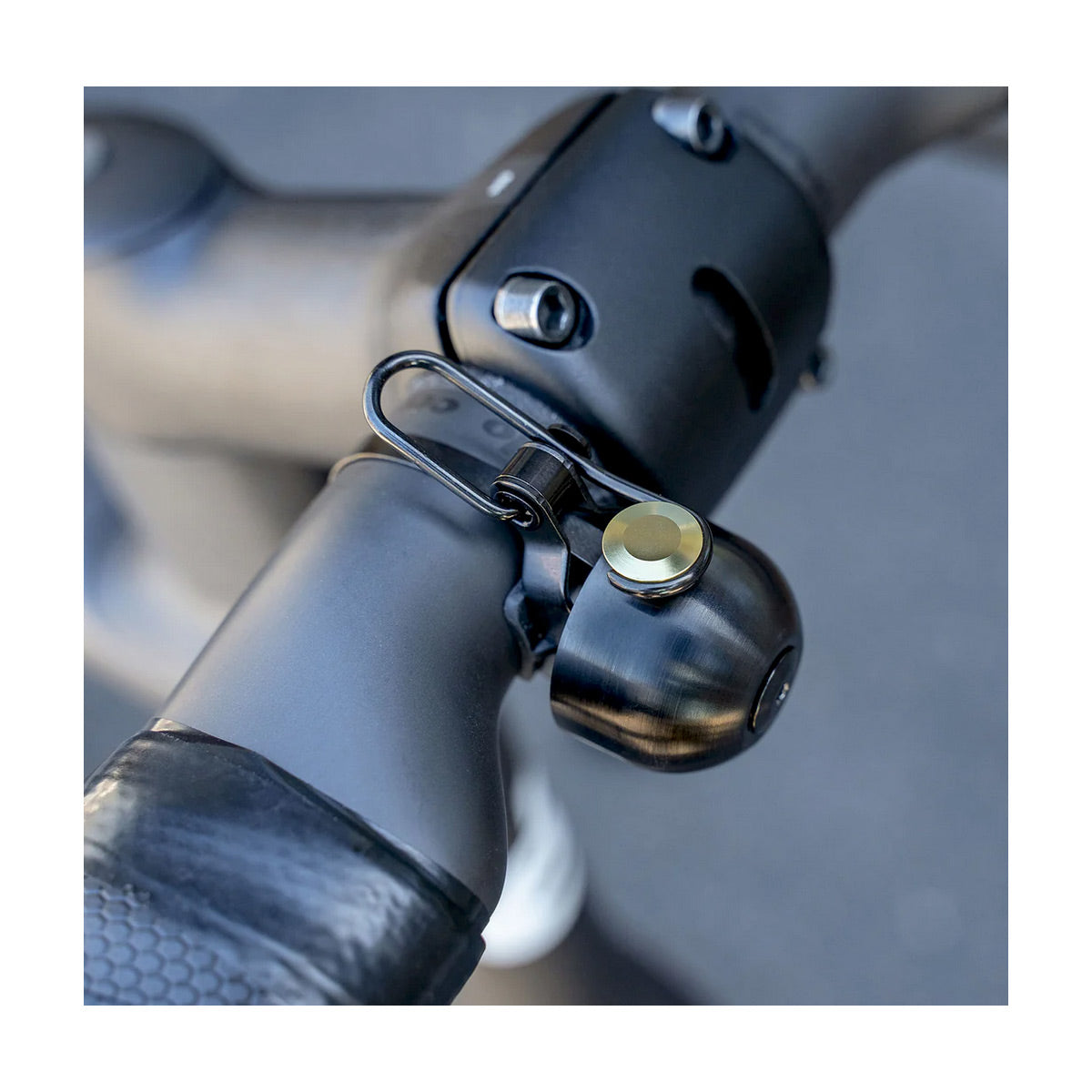 Close-up of a bike handlebar with a a black and gold bell attached