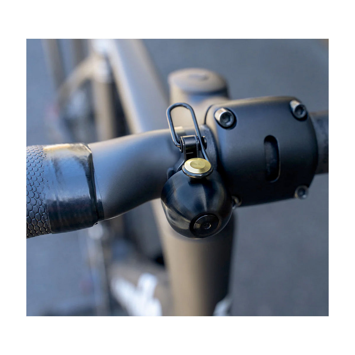 Close-up of a bicycle handlebar with a black and gold bell attached