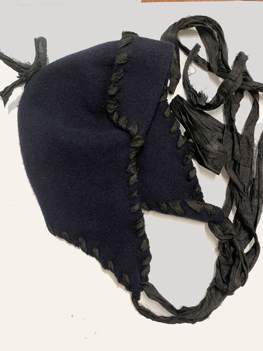 Navy blue wool toque with black tassels on a white background