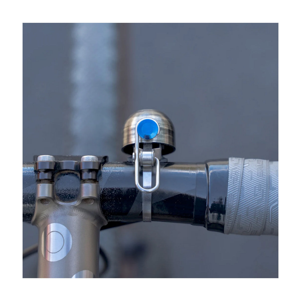 Close-up of a bicycle handlebar with a blue bell on a blurred background
