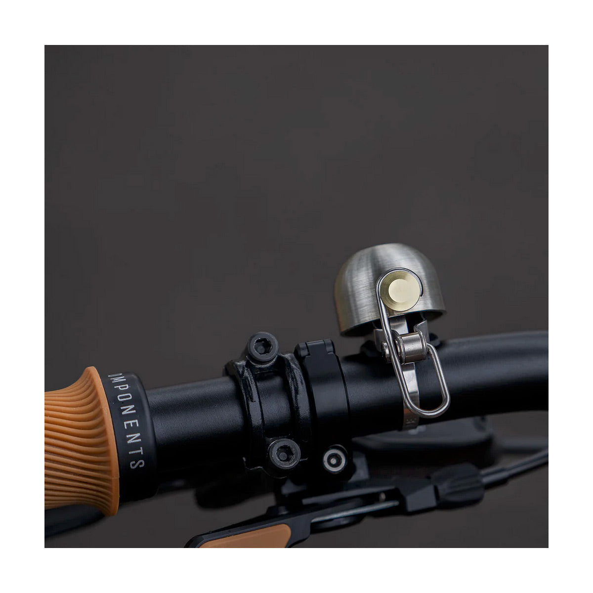 Close-up of a bicycle bell attached to a handlebar with a dark background