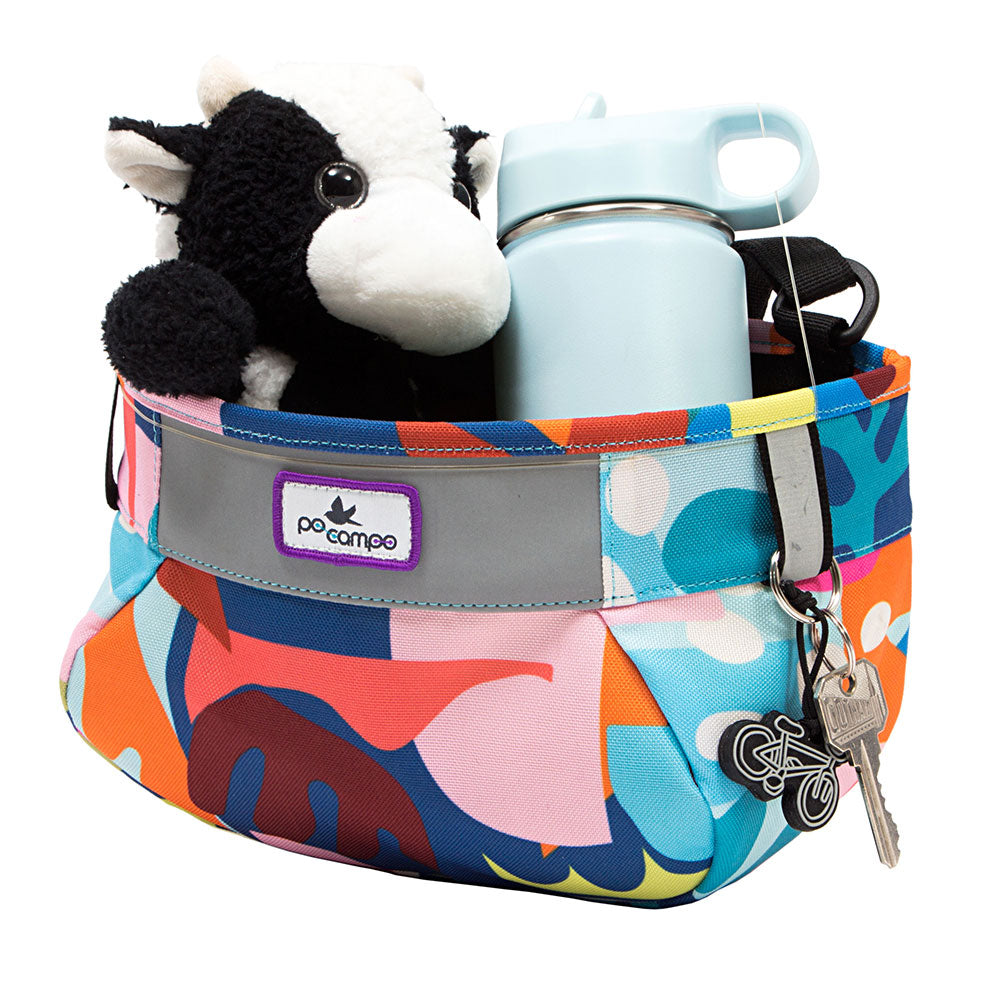 Colorful handlebar bag with plush cow toy, water bottle, and keys on a white background