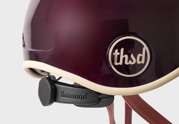 Close-up of a maroon helmet with 'thsd' logo and 'thousand' brand name on a white background