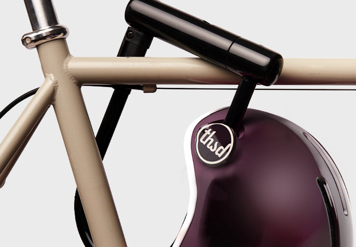 Close-up of a bicycle with a purple helmet attached, featuring the 'thsd' brand logo.