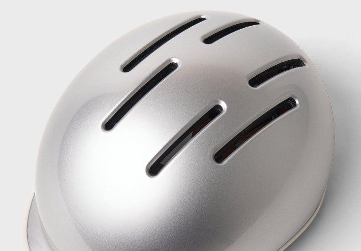 Silver helmet with ventilation on a light gray background