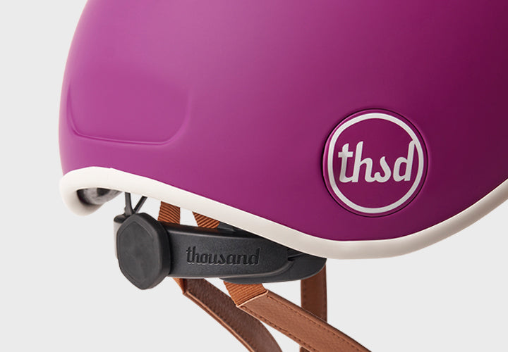 Close-up of urple helmet with 'thousand' brand name on a light gray background