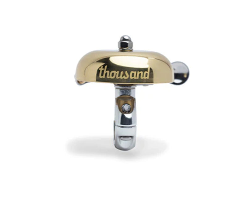 Gold and silver cycling bell with 'thousand' branding on a white background