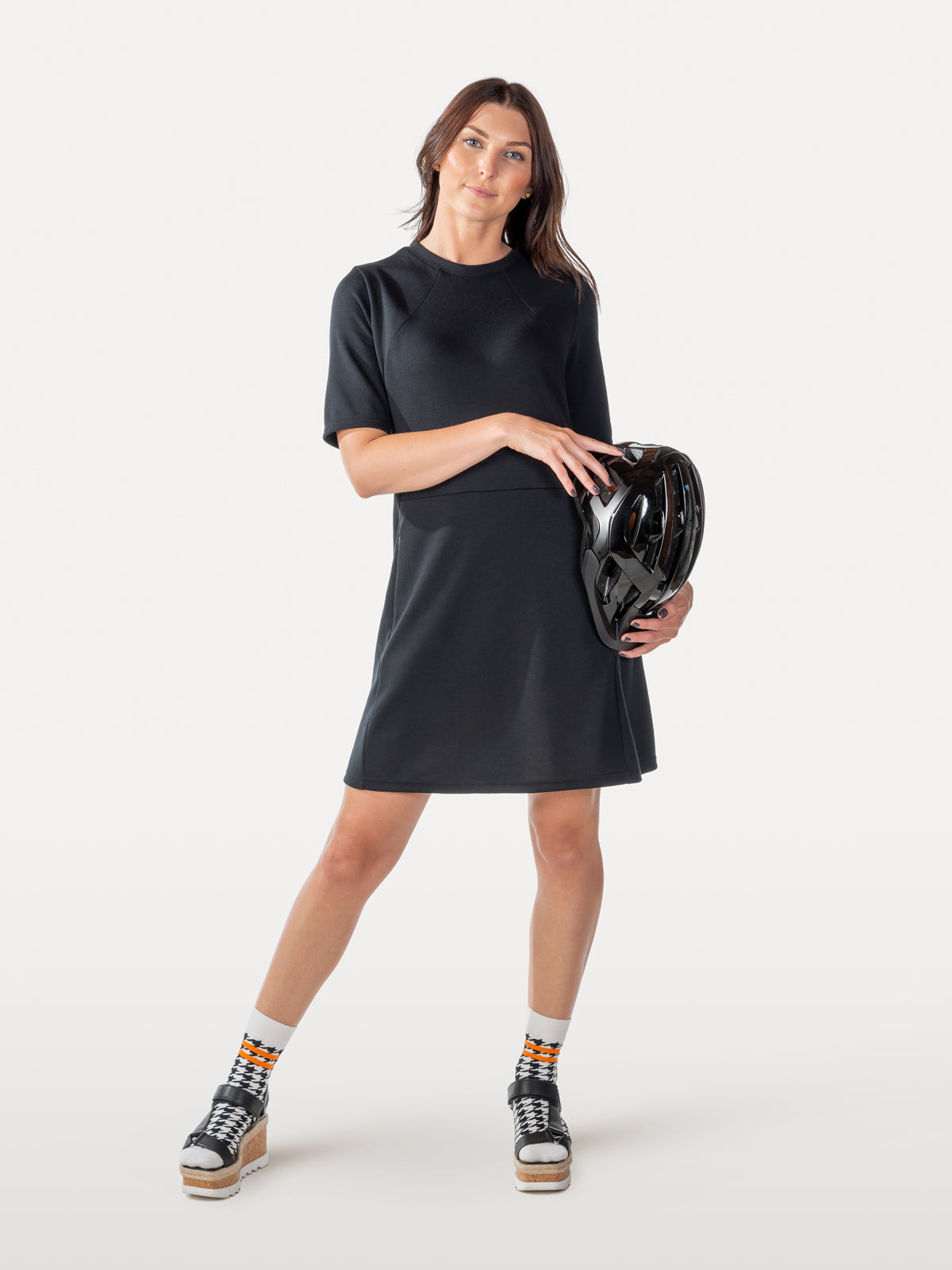 Woman in black cycling dress holds bike helmet