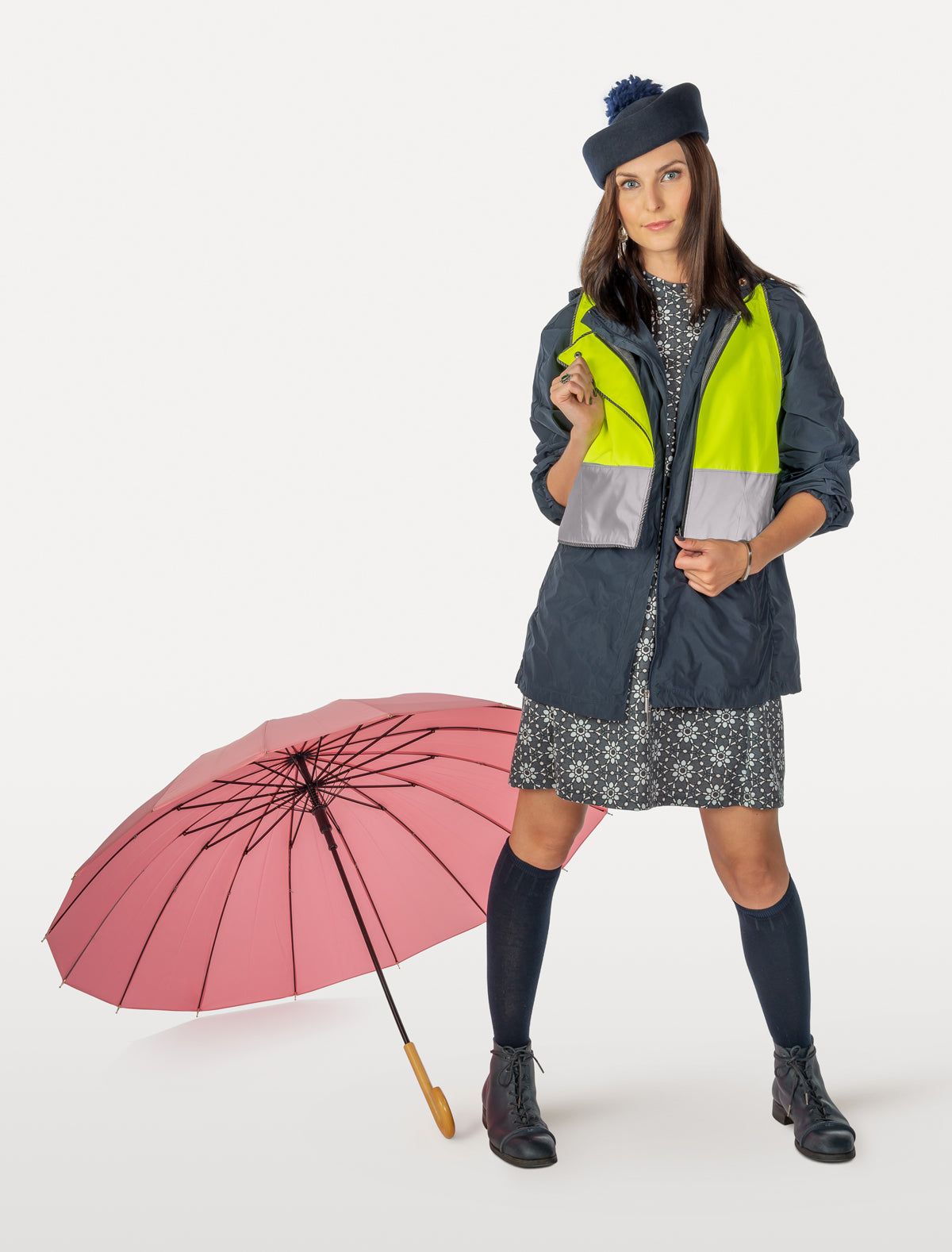 Daisies and heart-shaped patterned cycling dress under overcoat and reflective vest with pink umbrella
