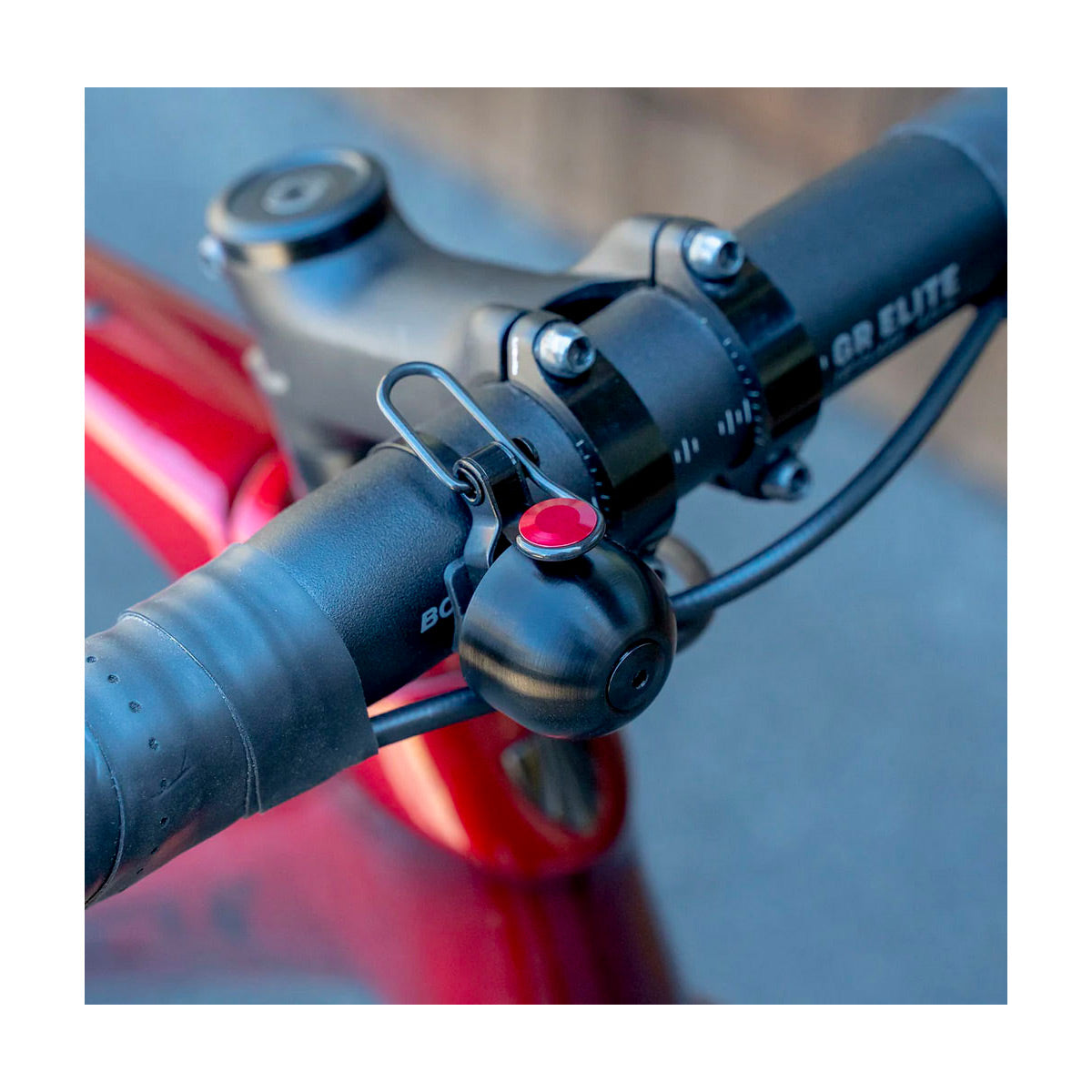 Close-up of bicycle handlebar with Spurcycle bike bell with red button on a blurred background