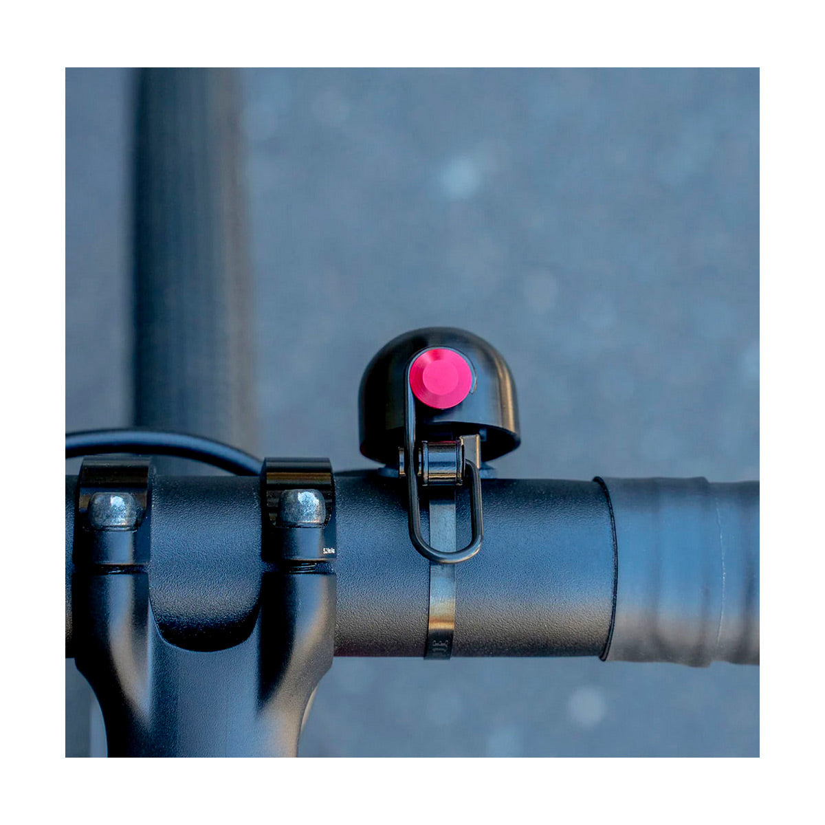 Bicycle bell with red button on handlebar against a blurred background
