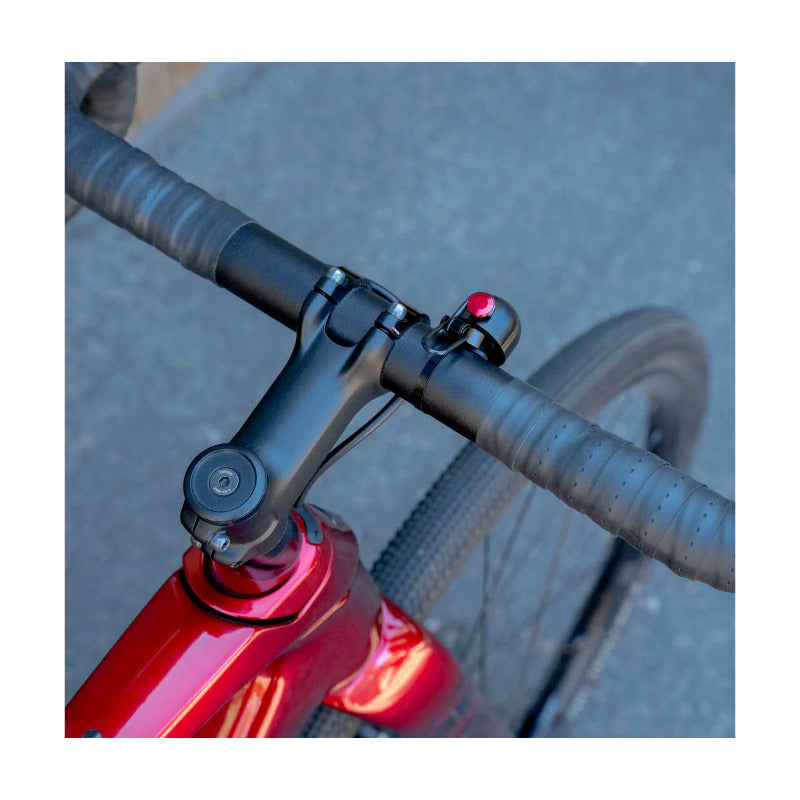 Close-up of a bicycle handlebar with black frame and red detail background