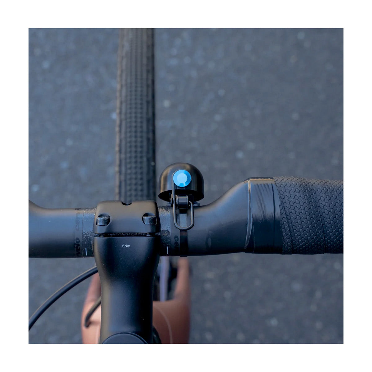 Close-up of a bicycle handlebar with a bike bell on a blurred road background