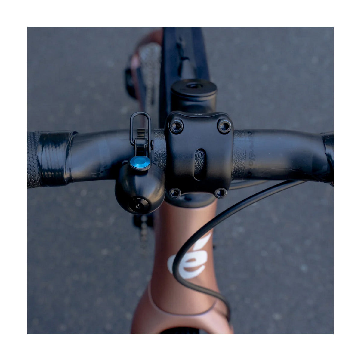 Close-up of a bicycle handlebar with a bicycle bell on a blurred road background