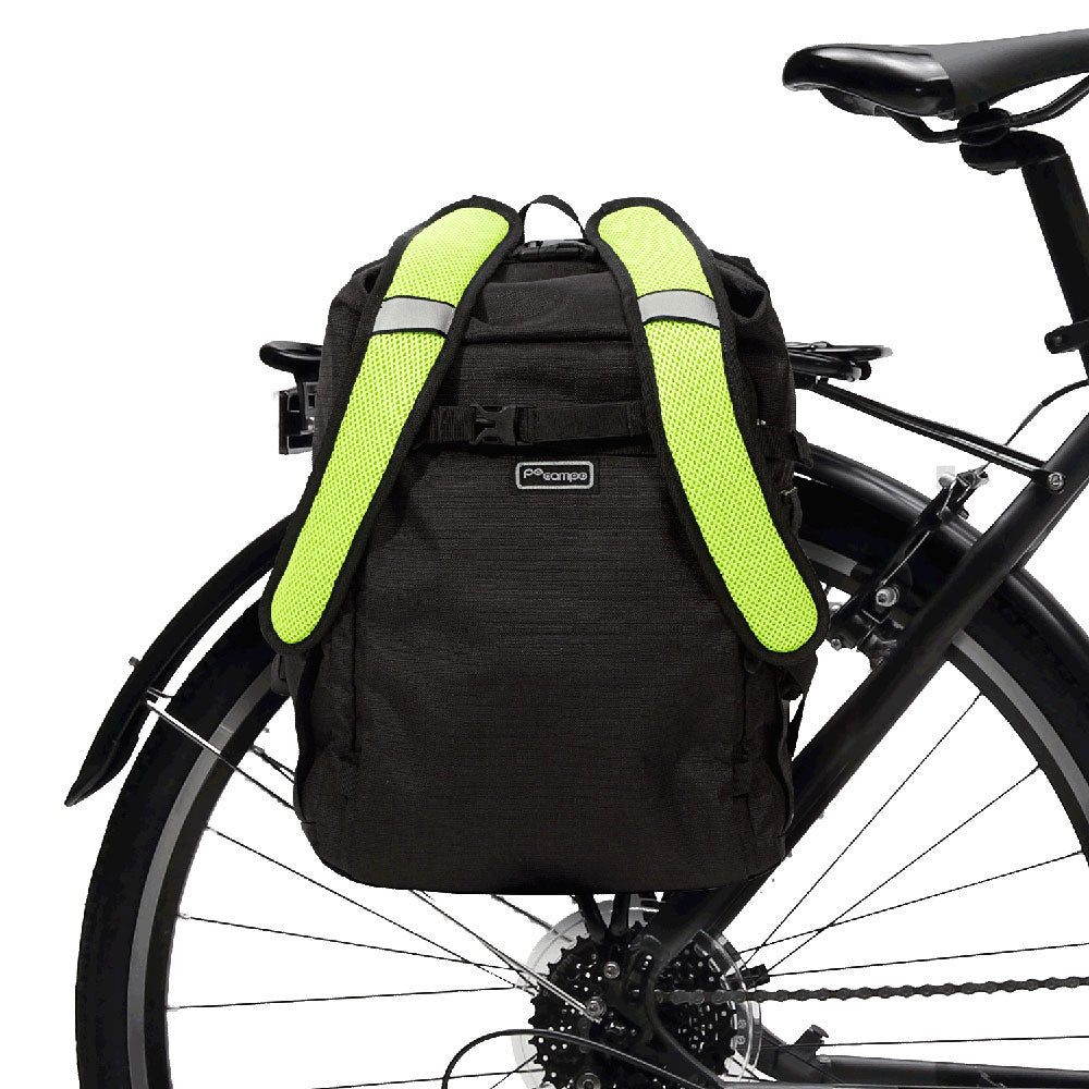 Black bicycle backpack pannier with reflective green straps attached to a bike on a white background