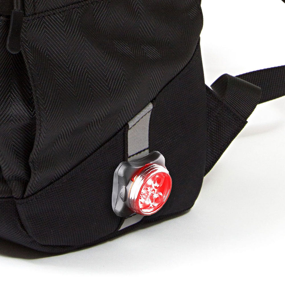Black backpack with a red light attached to it on a white background