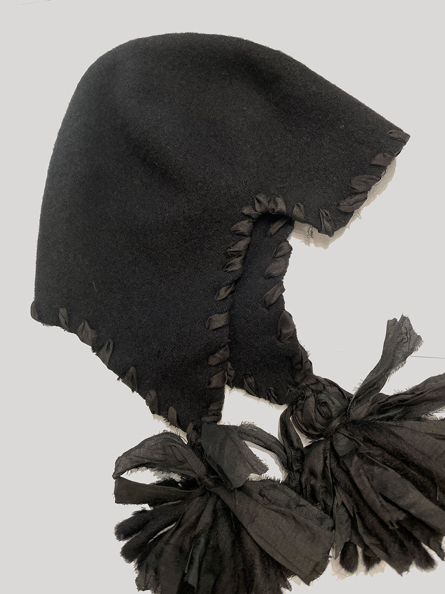 Black hooded toque with tassels on a light gray background