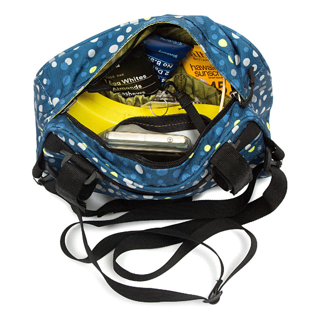 Blue polka dot handlebar bag with black straps, containing snacks and a phone on a white background