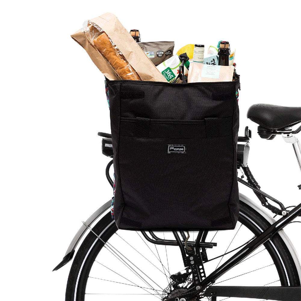 Black bicycle basket filled with groceries attached to a bike on a white background