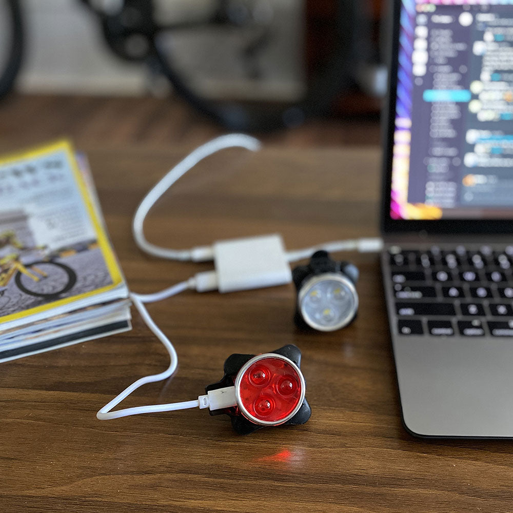 Rechargeable small red light device connected to a laptop on a wooden surface