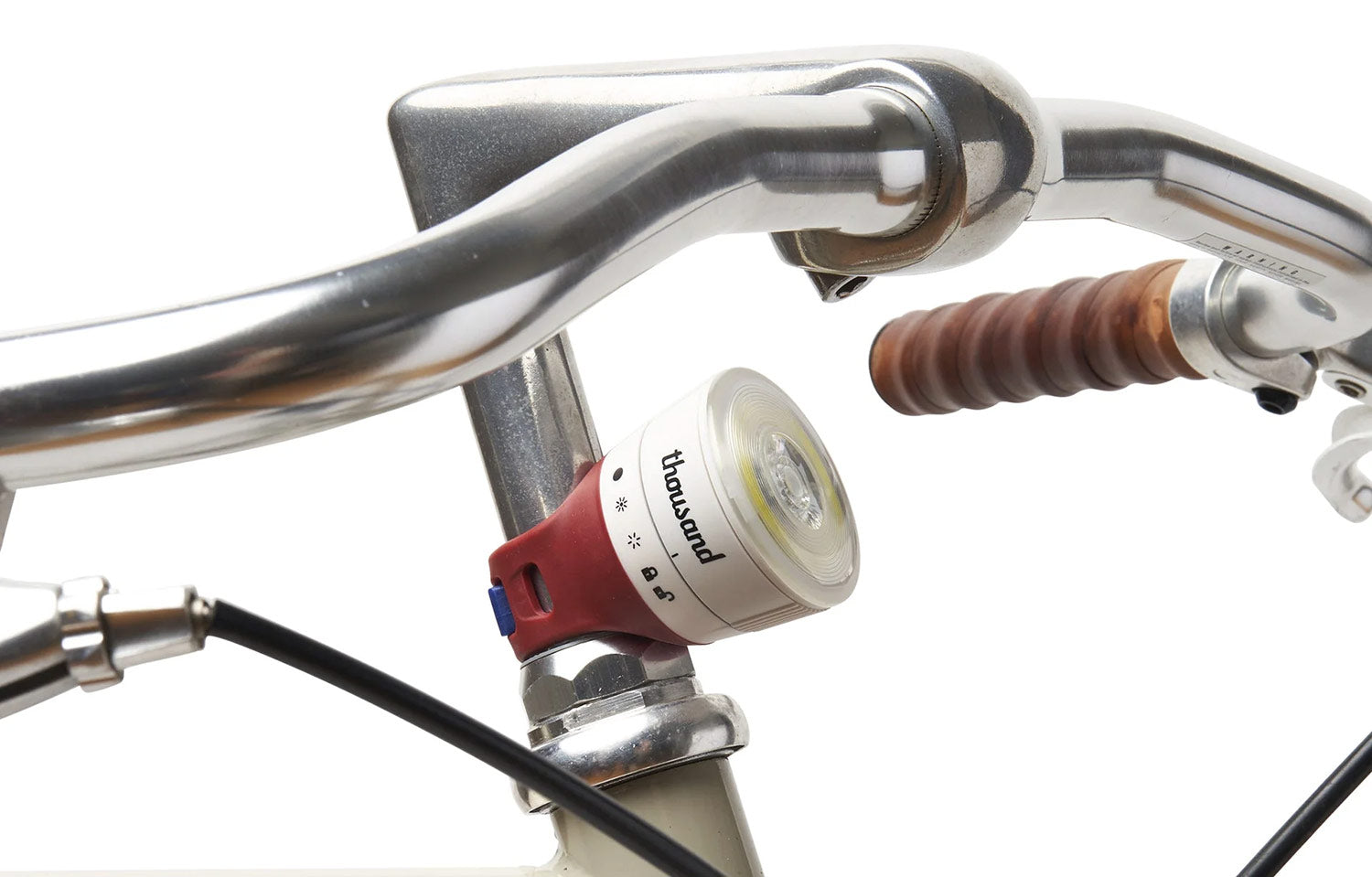 Bicycle handlebar with a front light attached, brand 'Thousand' visible