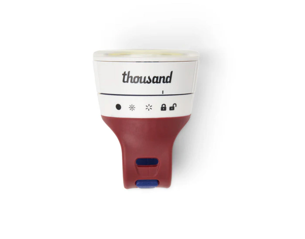 White and red detachable bicycle light with 'thousand' branding on a white background