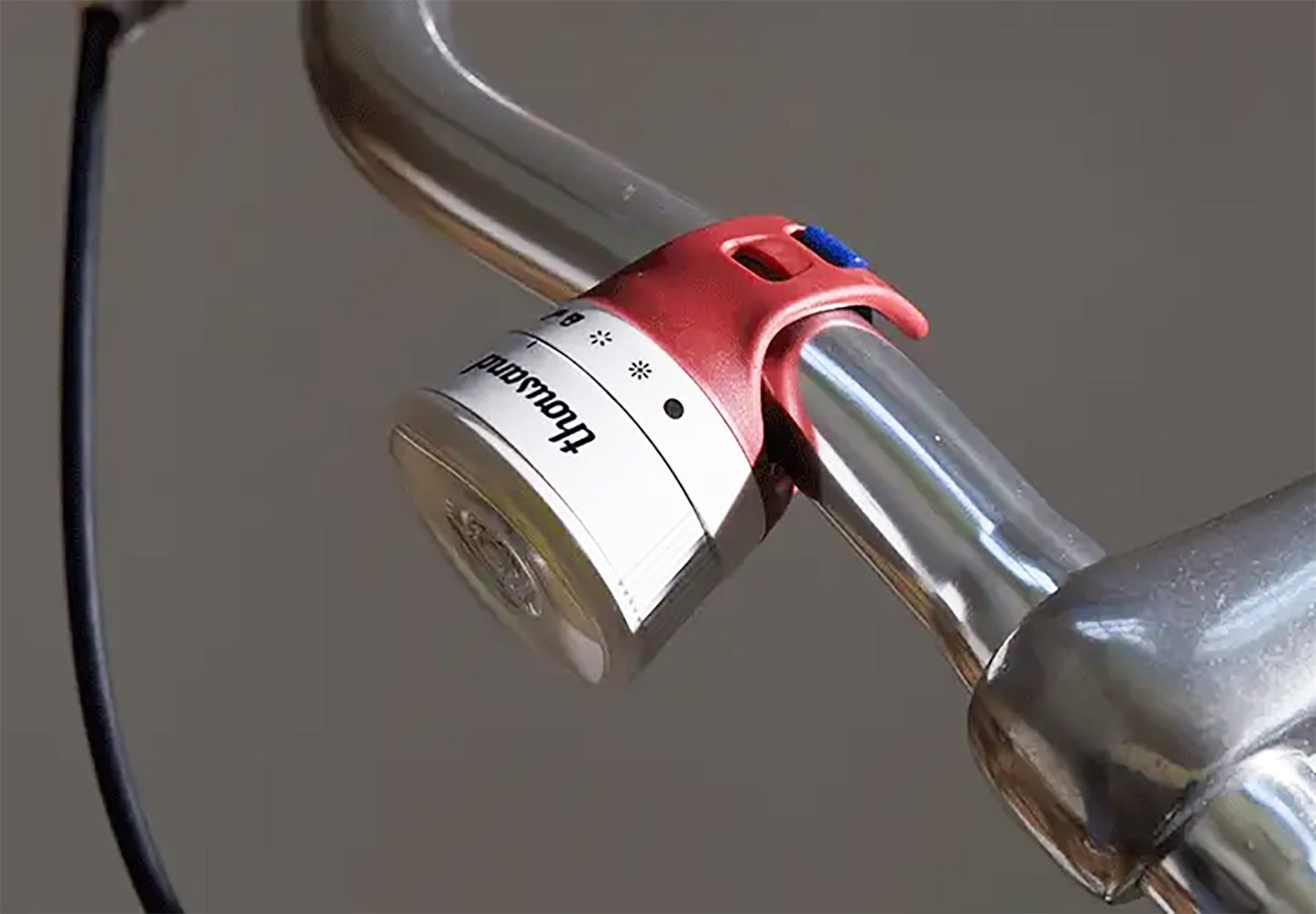 Bicycle light attached to handlebars with a neutral background