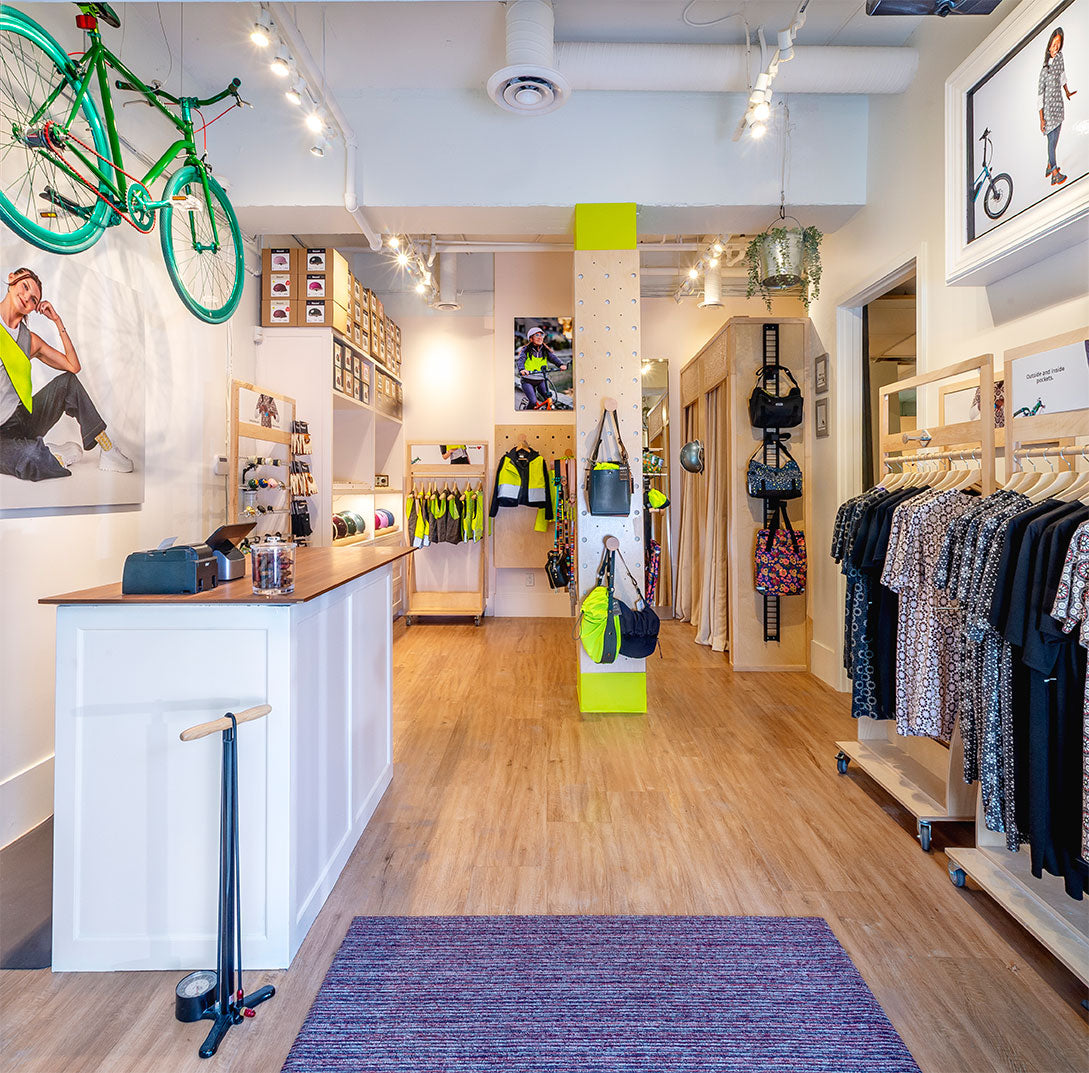 Interior of a store with clothing racks, a green bicycle, and various products on display.