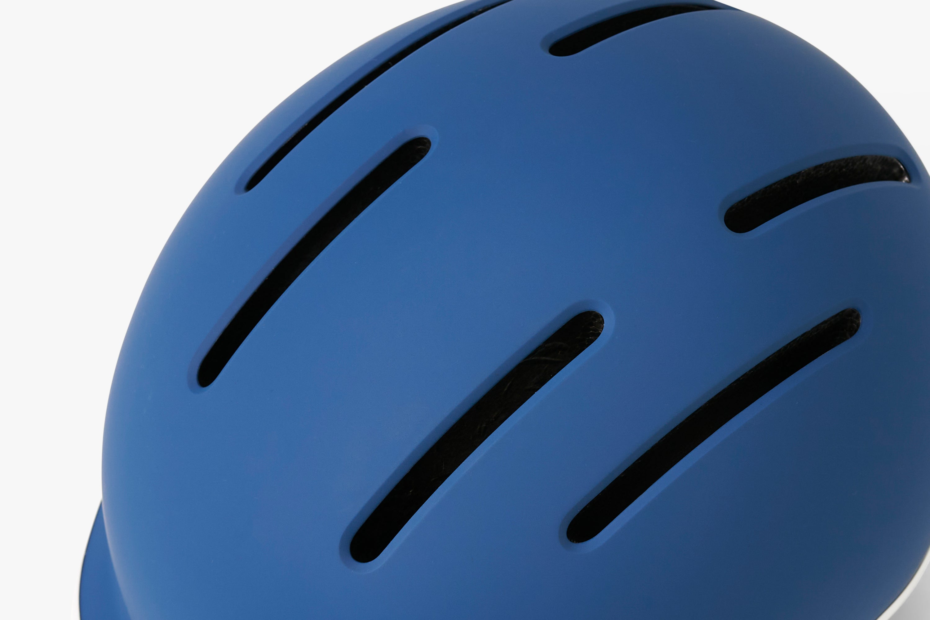 Close-up of a blue helmet with ventilation holes on a white background