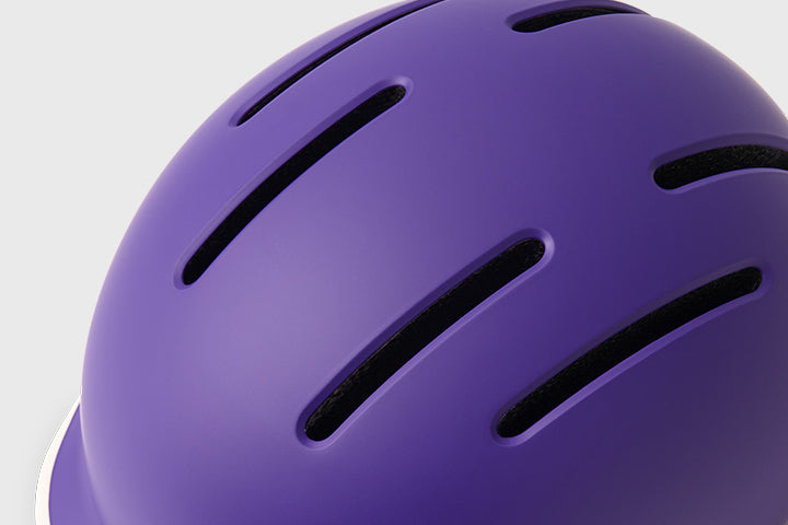 Close-up of a purple helmet with ventilation holes on a light gray background
