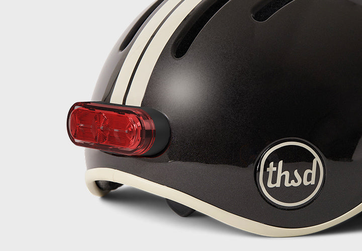 Black helmet with a red light and 'thsd' logo on a white background