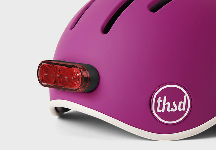 Purple helmet with a red light and 'thsd' logo on a white background