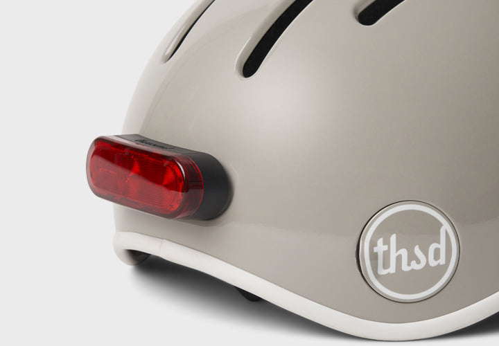 Close-up of a helmet with a red light and 'thsd' logo on a white background
