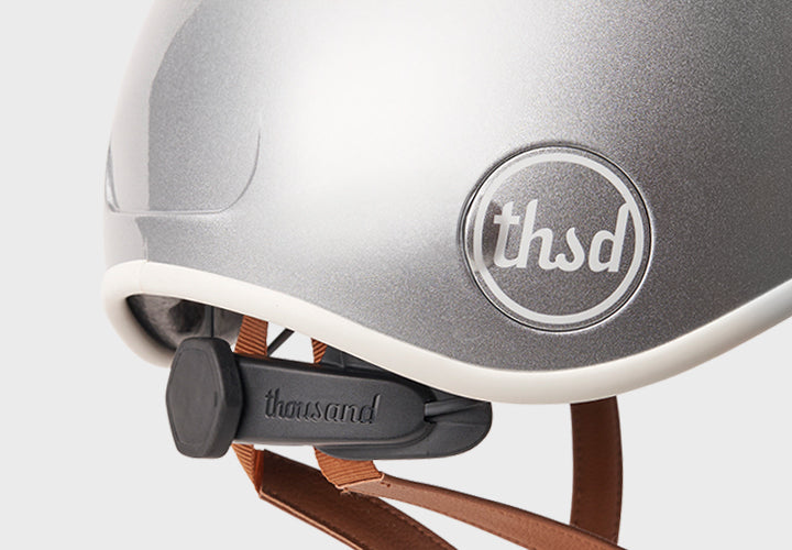Silver helmet with with fit adjustment on a grey background.