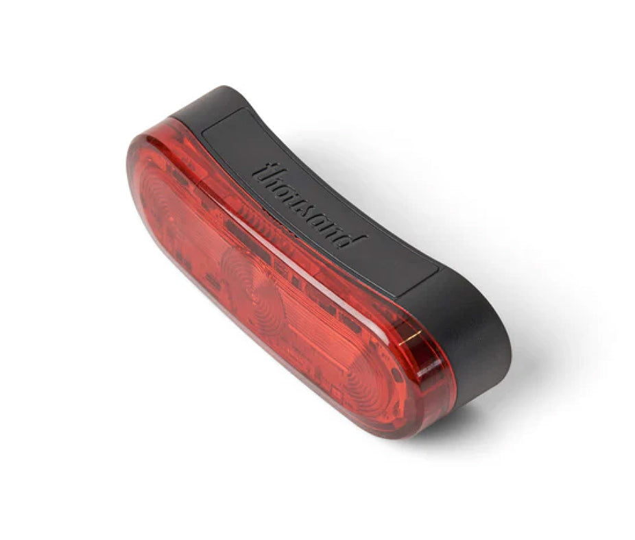 A red magnetic helmet light with a clear casing and a black mount, designed to be attached to the back of a helmet.