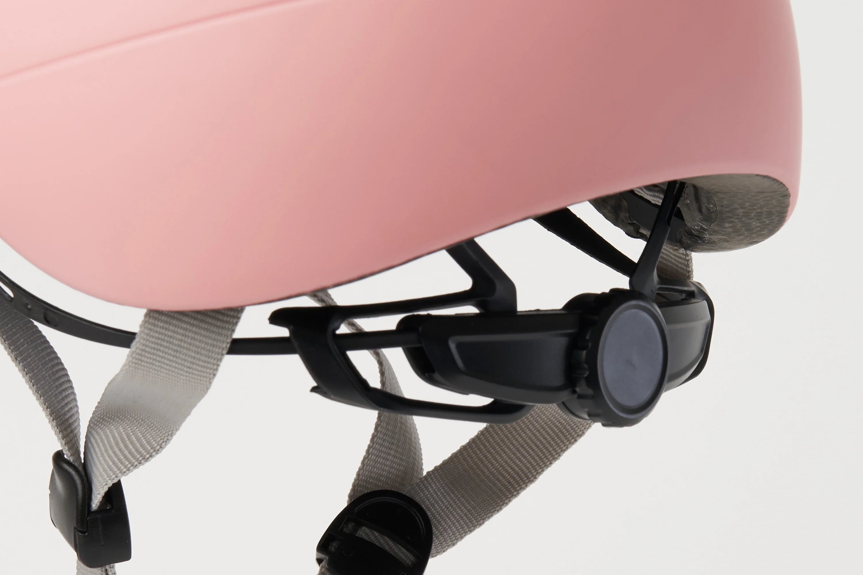 Close-up of a pink helmet with black straps and a white background