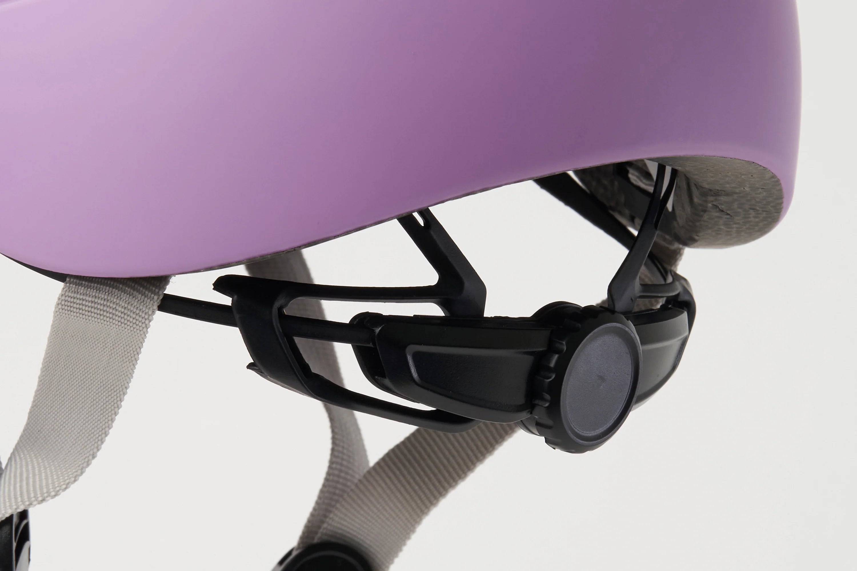Close-up of a purple helmet with black chin strap and gray straps on a light gray background