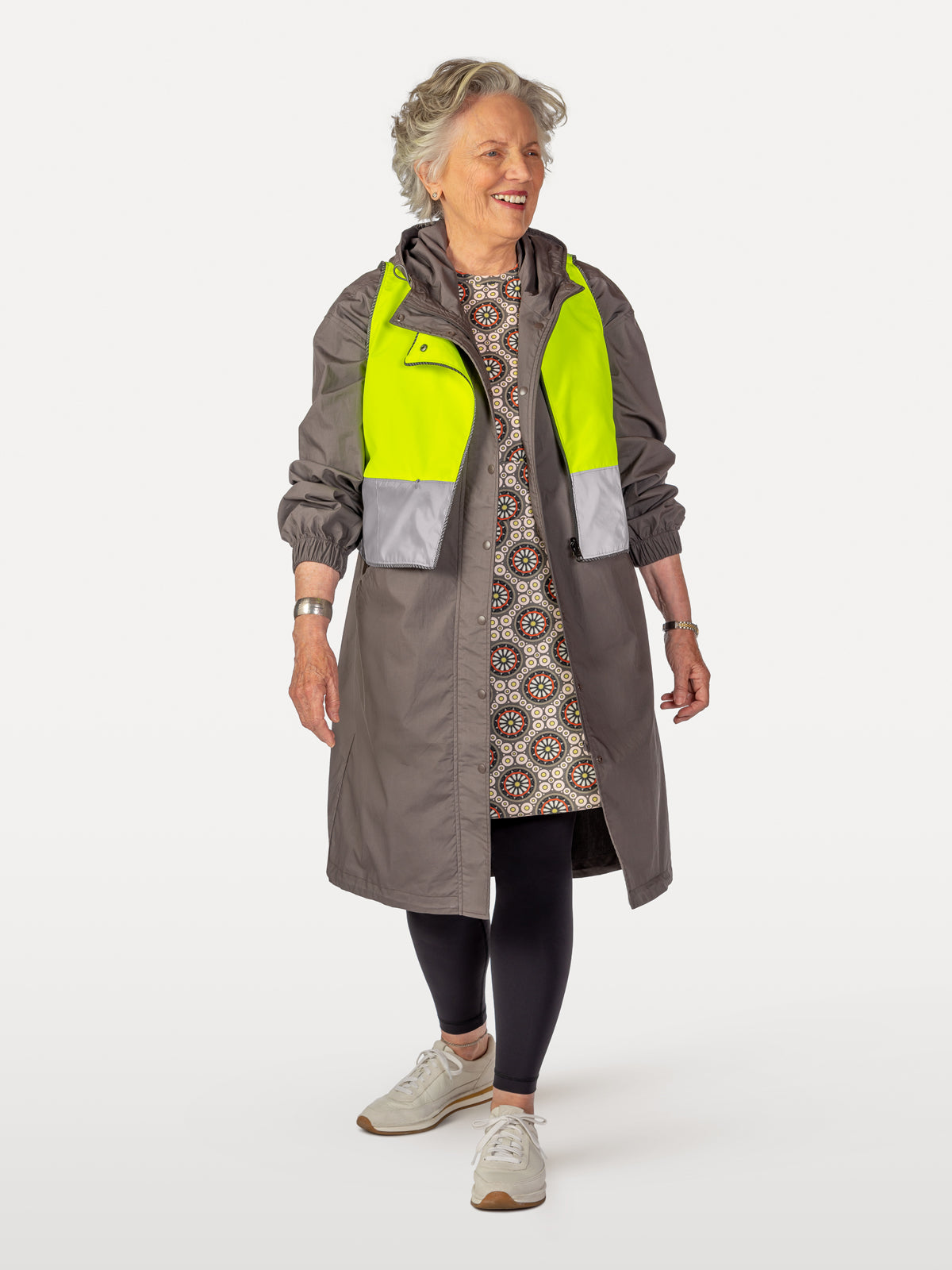 Spoke-patterned cycling dress under overcoat with reflective vest wearing black leggings